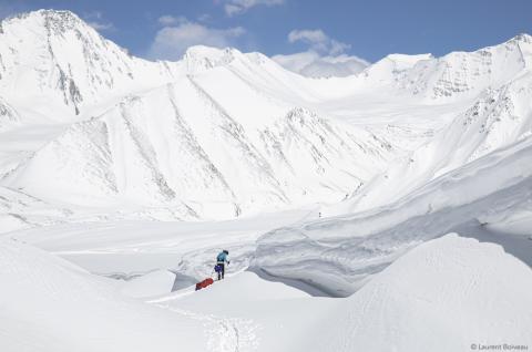 Skieur tirant sa pulka au pied du col du Lukpe La, cerné par les sommets enneigés du Karakoram