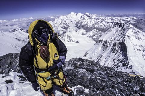 Alpiniste équipé pour la très haute altitude sur le versant nord de l'Everest, masque à oxygène et sommets himalayens enneigés en arrière-plan