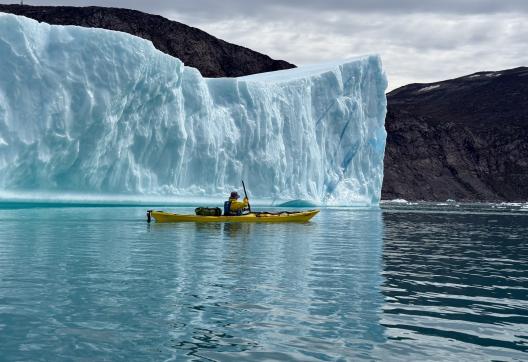 Kayakiste le long d'un immense Iceberg