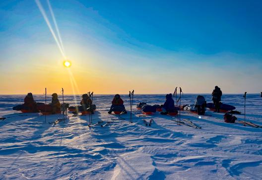 Expedition avec skieurs assis sur leurs pulkas durant une pause