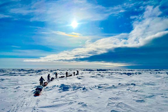 Expédition avec skieurs qui se suivent sous un nuage menaçant