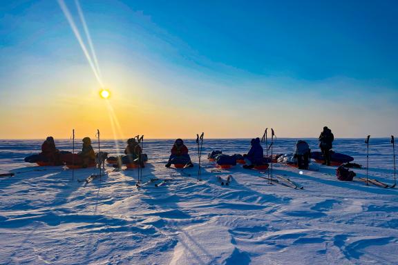 Expedition avec skieurs assis sur leurs pulkas durant une pause