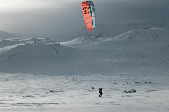 Snowkiteur par vent de travers avec une voile rouge PEAK