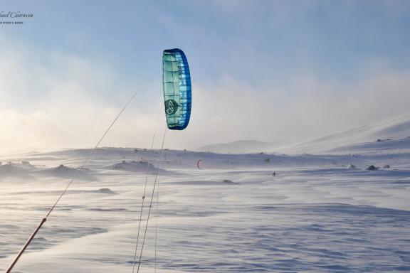 Snowkiteurs avec une voile bleue dans la tempête