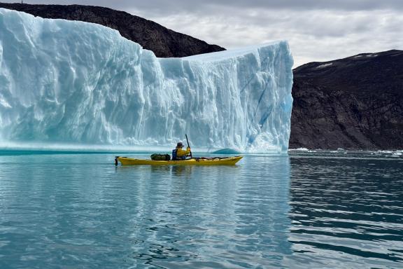 Kayakiste le long d'un immense Iceberg