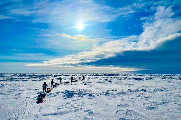 Expédition avec skieurs qui se suivent sous un nuage menaçant