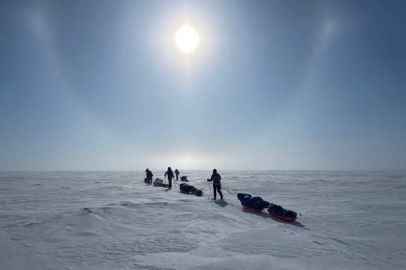 Expedition avec des skieurs qui avancent face au soleil lenticulaire au canada