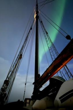 Observation d'une aurore boréale depuis le pont du voilier dans les fjords arctiques de Troms