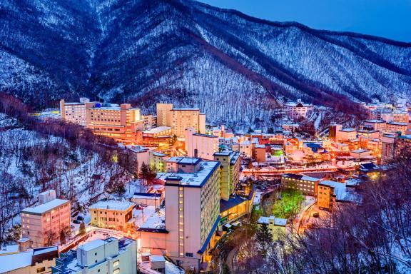 Voyage culturel dans un village thermal enneigé d’Hokkaido, entre hôtels japonais, montagnes enneigées et sources chaudes traditionnelles