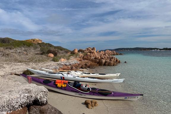 Voyage en kayak de mer avec débarquement sur une plage aux eaux translucides de l’archipel de La Maddalena, entourée de rochers granitiques et de maquis sarde