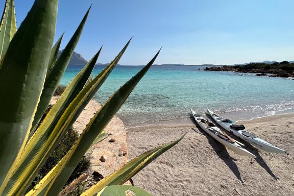 Voyage de deux kayaks de mer sur une plage de sable clair face à Tavolara en Sardaigne