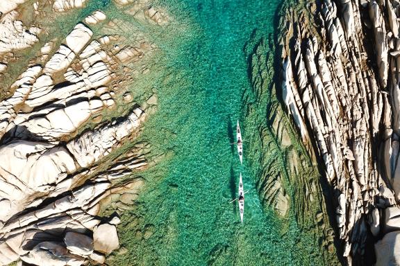 Expédition en kayak de mer vue du ciel dans les eaux turquoise de La Maddalena, entre couloirs rocheux, fonds clairs et granites sculptés de Sardaigne